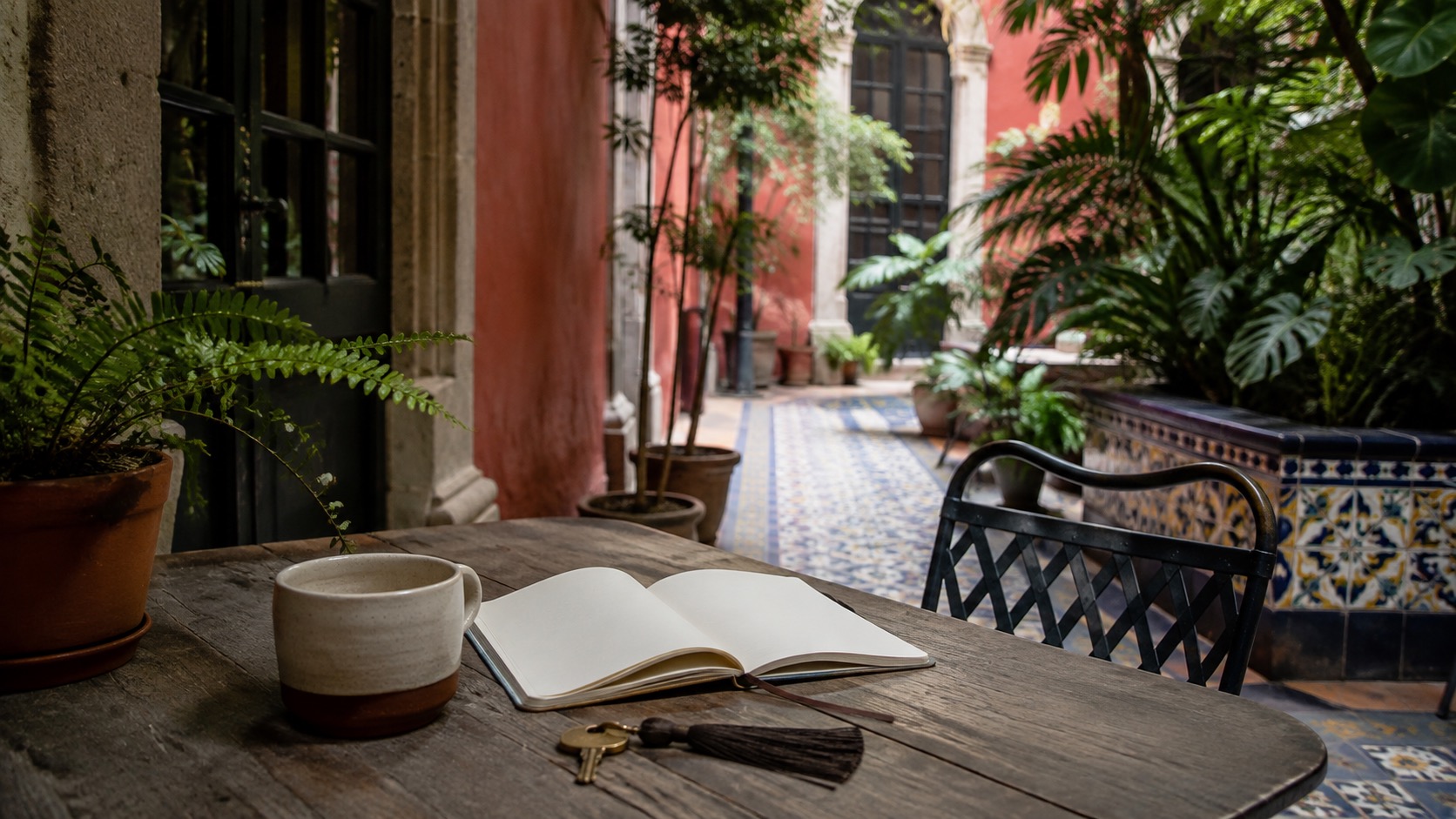 Innenhof in Mexiko-Stadt mit Keramiktasse, leerem Notizbuch, Schlüssel und Pflanzen