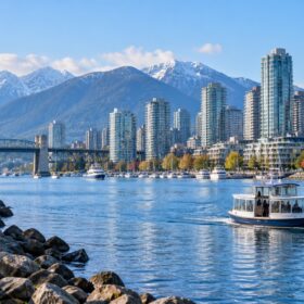 Vancouver Skyline mit kleiner Fähre, Wasser, Seawall und Bergen im Hintergrund